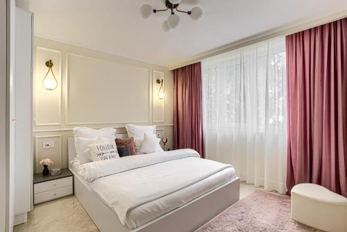 a bedroom with a white bed with red curtains at Sika DeLuxe Apartment in Arad