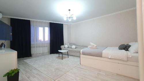 a white bedroom with a bed and a couch at 27 1 комн кв с кондиционером возле Байтерка на 4х человек in Astana