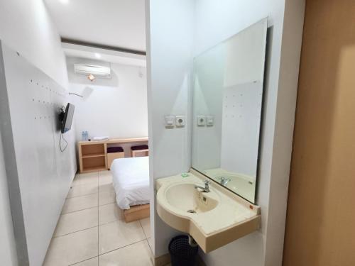a bathroom with a sink and a mirror and a bed at Urbanview Hotel B Liv Kendari in Puunggolaka