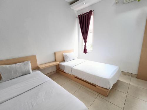 two beds in a room with a window at Urbanview Hotel B Liv Kendari in Puunggolaka