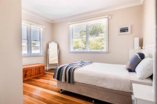 ein Schlafzimmer mit einem Bett und zwei Fenstern in der Unterkunft Rose Cottage in Devonport