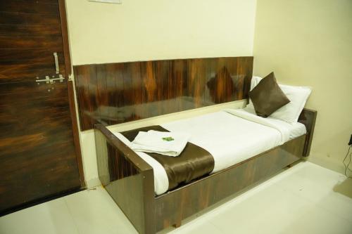 a small bed with a wooden headboard in a room at Hotel Sachidanand-Walkable distance from Temple in Shirdi