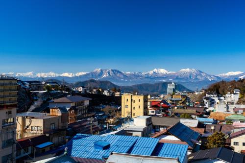 an aerial view of a city with mountains in the background at Suminoyu in Yamanouchi