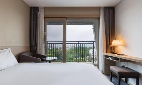 a hotel room with a bed and a balcony at The Best Jeju Seongsan in Seogwipo