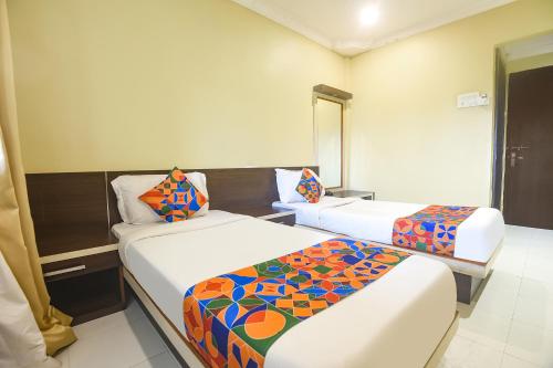 Cette chambre comprend 2 lits et un miroir. dans l'établissement FabExpress Sunrise By Vihasta, à Madgaon