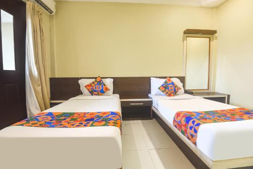 - 2 lits dans une chambre avec un miroir dans l'établissement FabExpress Sunrise By Vihasta, à Madgaon