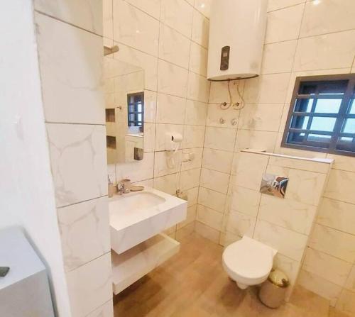 a white bathroom with a toilet and a sink at Les 9 Plurielles - Studio 2 KPALIME KOUMA KONDA in Palimé