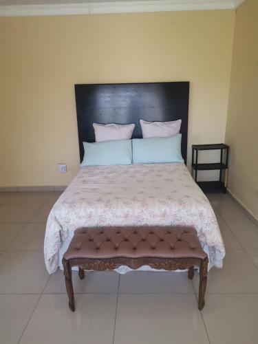 a bedroom with a large bed with a black headboard at Phakathi Lifestyle Village Umnini in Amanzimtoti