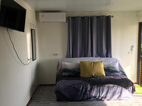 um quarto com uma cama com uma almofada amarela em Iaoraboraborahouse FAATAHI 1 em Bora Bora