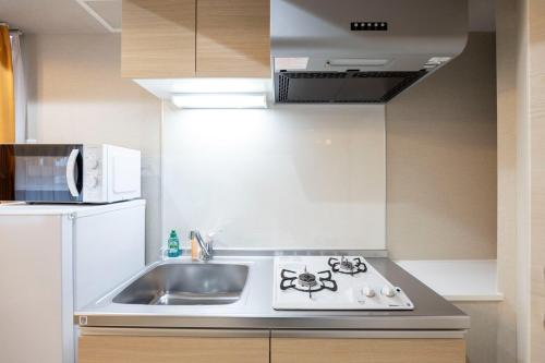 a small kitchen with a sink and a microwave at Mat Hikifune in Tokyo