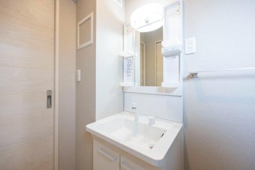 a white bathroom with a sink and a mirror at Mat Hikifune in Tokyo