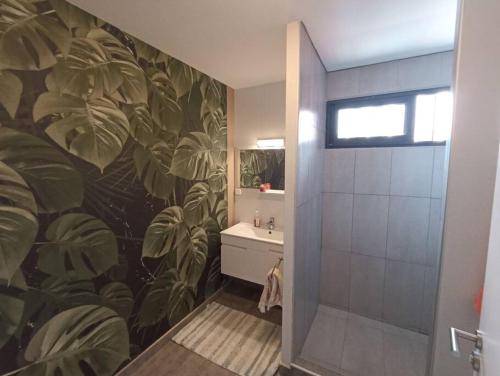 a bathroom with a large mural of leaves on the wall at Ravissante maison sur les hauteurs in Faaa