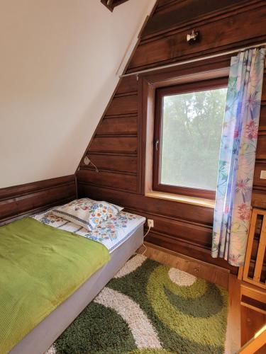 a small bedroom with a bed and a window at Chatka Kudłatka in Wetlina