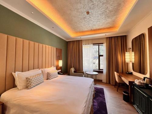 a hotel room with a large bed and a desk at Vivanta Tawang in Tawang