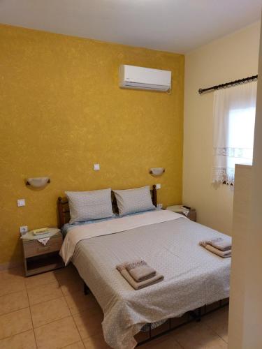 ein Schlafzimmer mit einem Bett und einer gelben Wand in der Unterkunft Armiriki Apartments in Korakokhórion