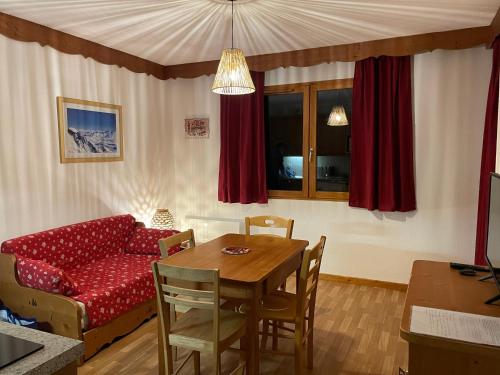 un salon avec une table et un canapé rouge dans l'établissement AU PIED DES PISTES D'ARVIEUX, à Arvieux