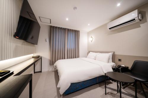 um quarto de hotel com uma grande cama branca e uma secretária em Baron De Hotel em Seul