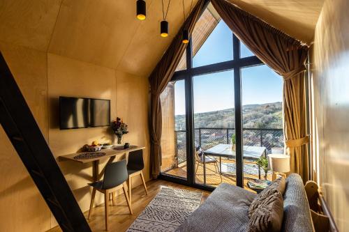 een woonkamer met een bank en een tafel en een groot raam bij Moose & Reindeer Cabin Chalets With A Panoramic View - Happy Rentals in Hosszúhétény-Szőlőhegy