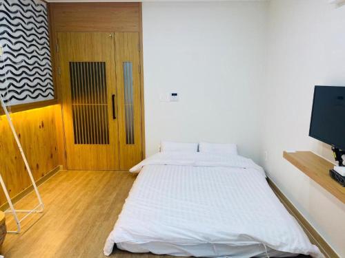 a bedroom with a white bed and a television at 38th Street Guesthouse in Mokpo