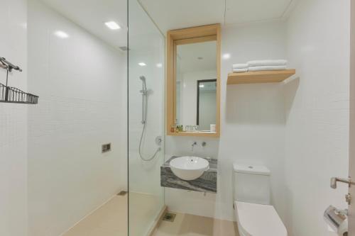 a white bathroom with a sink and a shower at Changi Cove in Singapore