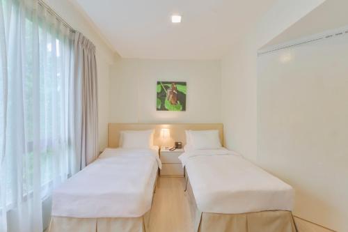 two beds in a white room with a window at Changi Cove in Singapore