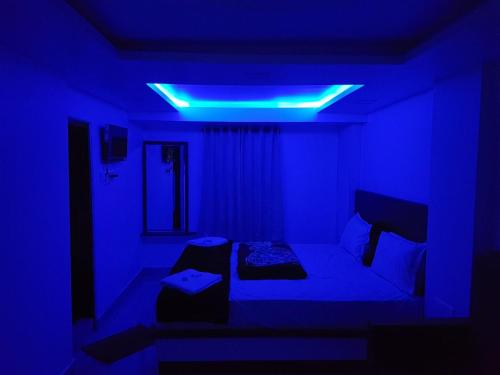 um quarto azul com uma cama e uma luz azul em Prakash home stay em Ooty