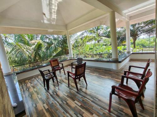 a room with chairs and a table and a balcony at Munroe La Casa in Kollam