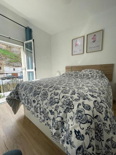 a bedroom with a bed with a black and white comforter at Casa Cuevas del Sol in Setenil