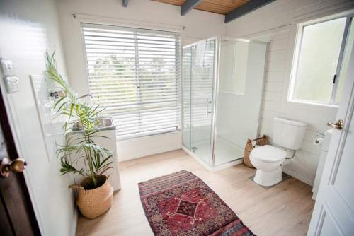 a bathroom with a toilet and a shower and a rug at Birdsong Train Carriage Cabins in Palmwoods