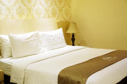 a bedroom with a bed with white sheets and pillows at Portola Grand Arabia Hotel in Banda Aceh