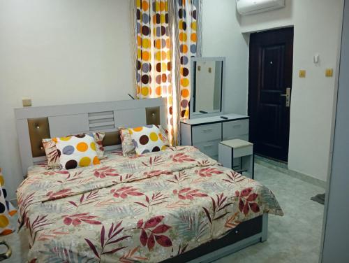 a bedroom with a bed with a floral bedspread at Frontline Homes & Suites 3bedroom Apartment in Lekki