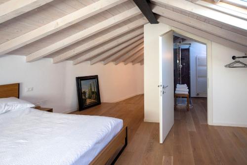 1 dormitorio con cama blanca y suelo de madera en Casa Tonde - Attico in palazzetto storico, en Bassano del Grappa