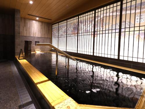 una piscina de agua en un edificio con un banco en Onyado Nono Asakusa Bettei Hot Spring, en Tokio