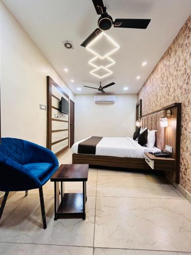 ein Schlafzimmer mit einem Bett und einem blauen Stuhl in der Unterkunft HOTEL MONGA 5 Minutes From Golden Temple in Amritsar