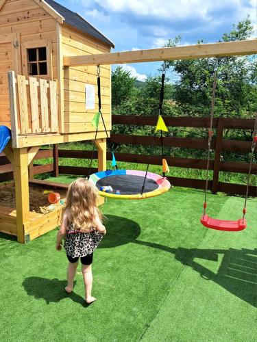a little girl standing in front of a playground at Całoroczne Domki Wypoczynkowe - Osada pod Górą in Ustrzyki Dolne