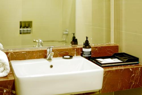 a bathroom with a white sink and a mirror at Portola Grand Arabia Hotel in Banda Aceh