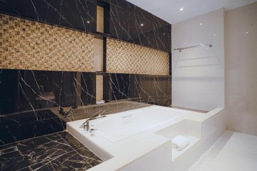 uma casa de banho com um lavatório branco e azulejos pretos em Portola Grand Arabia Hotel em Banda Aceh