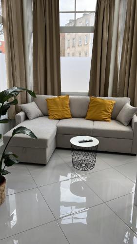 a living room with a couch with yellow pillows and a table at Stylish Flat in Camden/KingsCross in London