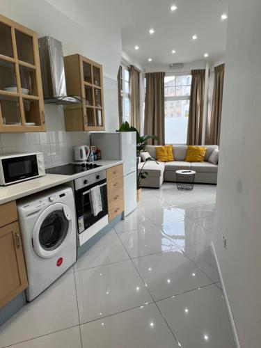 a kitchen with a washing machine and a living room at Stylish Flat in Camden/KingsCross in London