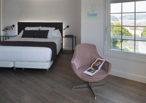 Un dormitorio con una cama y una silla con un libro. en Hotel Avenida en San Sebastián