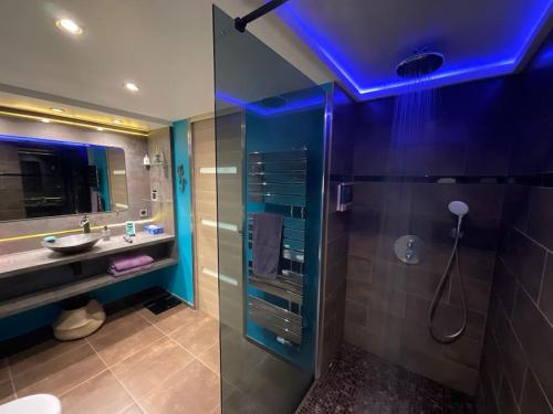 La salle de bains est pourvue d'un lavabo et d'une douche avec une lumière bleue. dans l'établissement Logement 4 personnes avec cuisine équipée et parking clos, à Mouroux