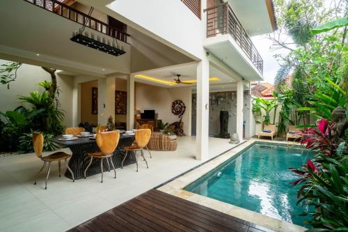 a villa with a swimming pool and a dining area at La Rose Villas and Suites Camp Canggu in Canggu