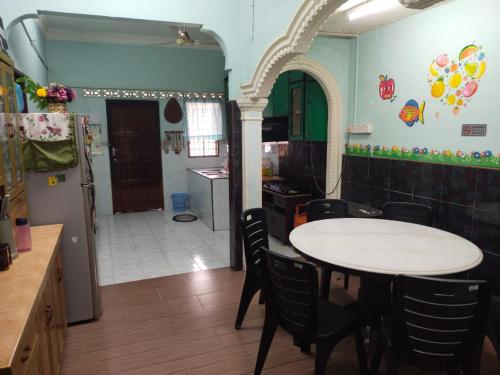een keuken met een tafel en stoelen in een kamer bij Semarak Homestay in Baling