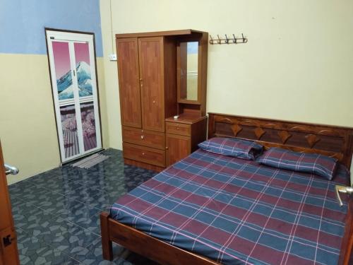 Schlafzimmer mit einem Bett, einer Kommode und einem Spiegel in der Unterkunft Semarak Homestay in Baling