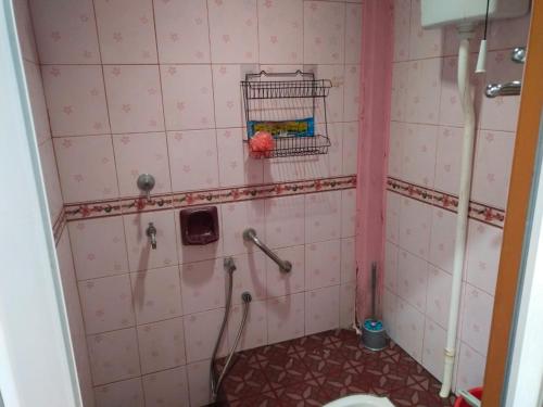 ein Badezimmer mit einer rosa gefliesten Dusche und einem WC in der Unterkunft Semarak Homestay in Baling