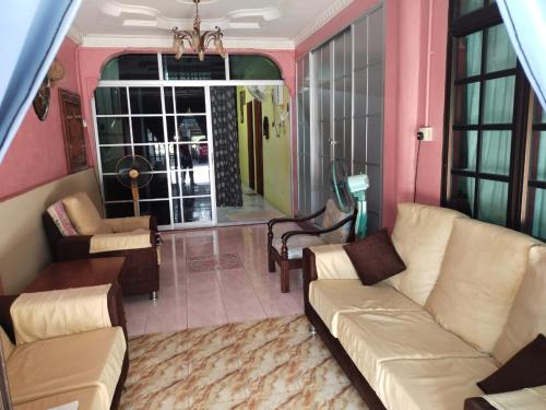 een woonkamer met een bank, stoelen en een tafel bij Semarak Homestay in Baling