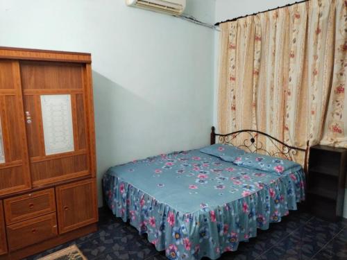 een kleine slaapkamer met een bed en een dressoir bij Semarak Homestay in Baling
