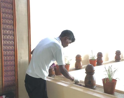 a man standing in front of a window next to plants at Hotel Indsurya in Dibrugarh