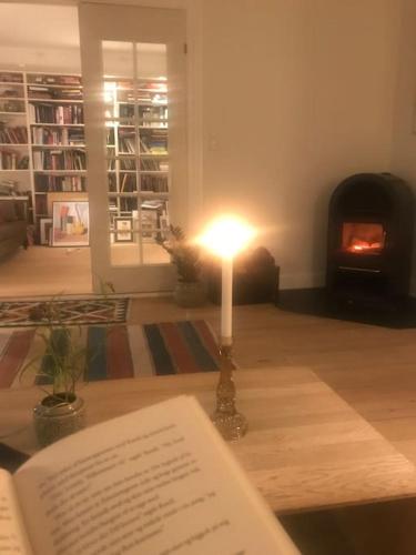 eine Kerze auf einem Tisch mit einem Buch und einem Kamin in der Unterkunft Smukt, sjælfuldt og charmerende hus midt i Odense. in Odense