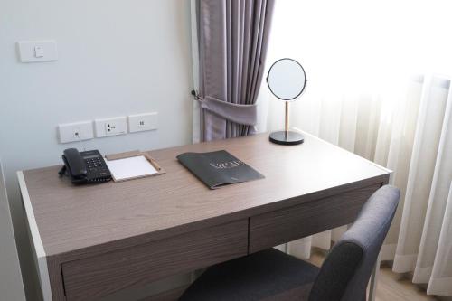 a desk with a phone and a mirror on it at The Rise Suites Hotel, Chiang Mai - SHA Extra Plus in Chiang Mai